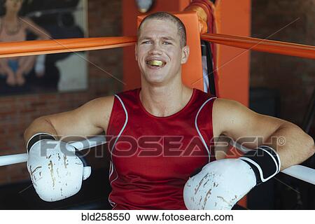 Stock Image - Portrait of Caucasian boxer sitting in corner of boxing ring. Fotosearch