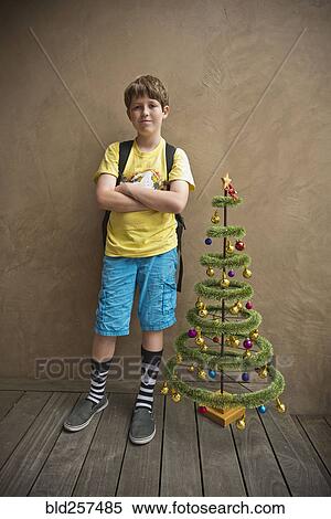 Portrait of Caucasian boy standing near small artificial Christmas tree View Large Photo Image Stock Photography - Portrait of Caucasian boy standing near small artificial Christmas tree. Fotosearch