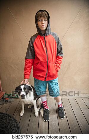 Stock Photography - Portrait of Caucasian boy standing with dog. Fotosearch