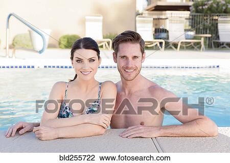 Stock Image - Portrait of Caucasian couple in swimming pool. Fotosearch