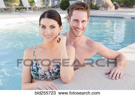 Stock Image - Portrait of Caucasian couple in swimming pool. Fotosearch