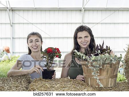 Stock Image - Portrait of Caucasian mother and daughter holding flowers. Fotosearch