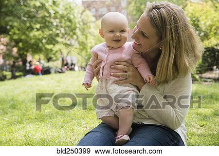 Portrait of Caucasian mother holding baby daughter in park View Large Photo Image Stock Photo - Portrait of Caucasian mother holding baby daughter in park. Fotosearch