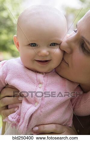 Portrait of Caucasian mother kissing cheek of baby daughter View Large Photo Image Stock Image - Portrait of Caucasian mother kissing cheek of baby daughter. Fotosearch