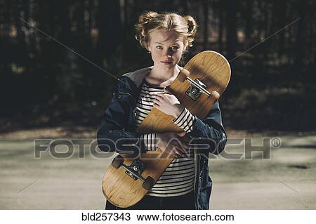 Stock Image - Portrait of Caucasian teenage girl holding skateboard. Fotosearch