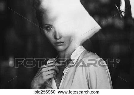 Stock Image - Portrait of Caucasian woman behind window. Fotosearch