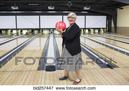 Portrait of Caucasian woman holding bowling ball near lane View Large Photo Image Stock Photo - Portrait of Caucasian woman holding bowling ball near lane. Fotosearch