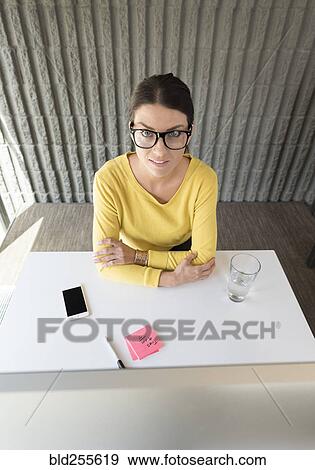 Stock Photo - Portrait of Caucasian woman sitting at desk. Fotosearch