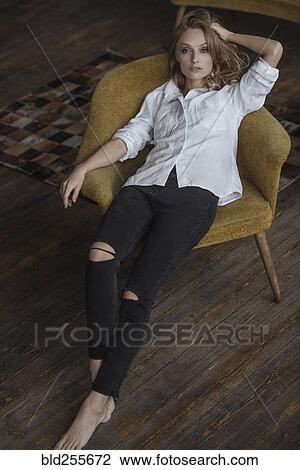 Stock Image - Portrait of Caucasian woman sitting in armchair. Fotosearch