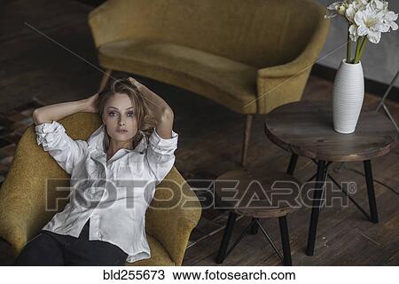 Stock Image - Portrait of Caucasian woman sitting in armchair. Fotosearch