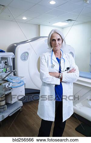 Stock Photograph - Portrait of confident Caucasian doctor near scanner. Fotosearch