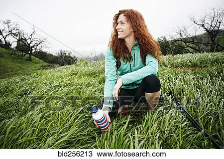 Portrait of crouching Caucasian woman holding bottle View Large Photo Image Stock Image - Portrait of crouching Caucasian woman holding bottle. Fotosearch