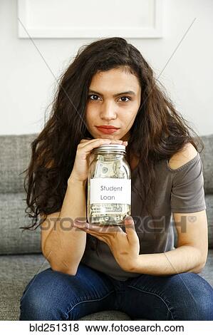 Portrait of mixed race woman holding jar of money for student loan View Large Photo Image Stock Photo - Portrait of mixed race woman holding jar of money for student loan. Fotosearch
