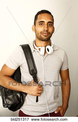Stock Photo - Portrait of nixed race man with headphones and backpack. Fotosearch