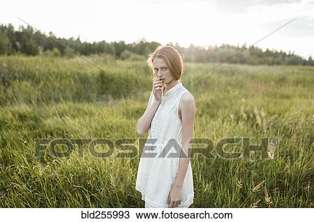Stock Image - Portrait of pensive Caucasian girl standing in field. Fotosearch