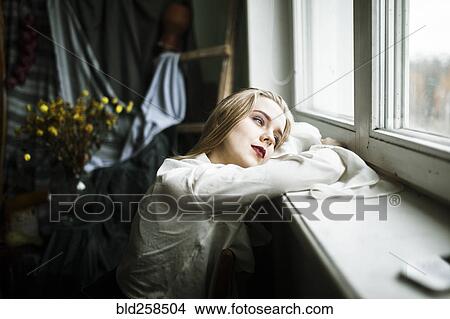 Picture - Portrait of pensive Caucasian woman leaning on window sill. Fotosearch
