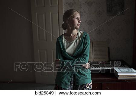 Stock Image - Portrait of pensive Caucasian woman leaning on piano. Fotosearch