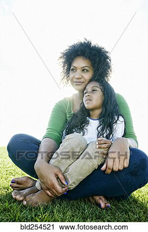 Portrait of pensive mixed race mother and daughter sitting in grass View Large Photo Image Stock Image - Portrait of pensive mixed race mother and daughter sitting in grass. Fotosearch