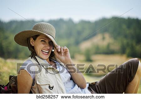 Stock Photo - Portrait of playful Hispanic woman pulling brim of hat. Fotosearch