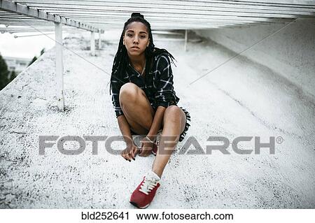 Portrait of serious African American woman sitting on concrete View Large Photo Image Stock Image - Portrait of serious African American woman sitting on concrete. Fotosearch