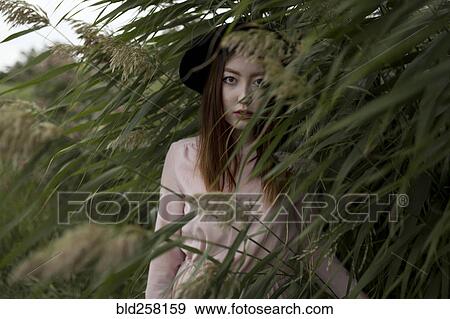 Portrait of serious Asian woman standing in field of tall grass View Large Photo Image Stock Photo - Portrait of serious Asian woman standing in field of tall grass. Fotosearch