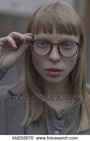 Stock Image - Portrait of serious Caucasian woman holding eyeglasses. Fotosearch