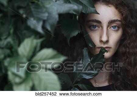 Portrait of serious Caucasian woman behind leaves View Large Photo Image Stock Image - Portrait of serious Caucasian woman behind leaves. Fotosearch