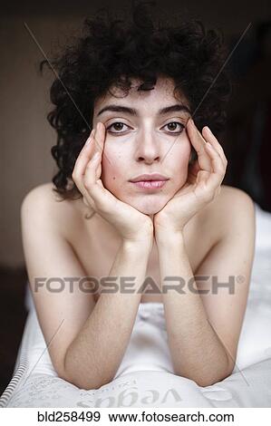 Stock Photo - Portrait of serious Caucasian woman laying on bed. Fotosearch