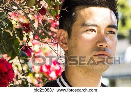 Stock Photo - Portrait of serious Chinese man near flowering tree. Fotosearch