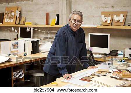 Picture - Portrait of serious Hispanic designer examining color swatches in office. Fotosearch