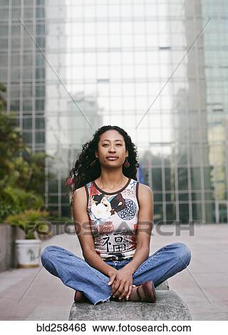 Stock Photo - Portrait of serious mixed race woman sitting near highrise. Fotosearch
