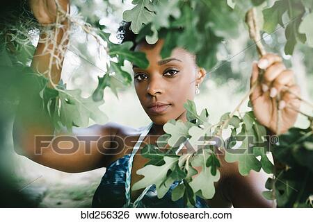 Stock Photograph - Portrait of serious mixed race woman holding tree branches. Fotosearch