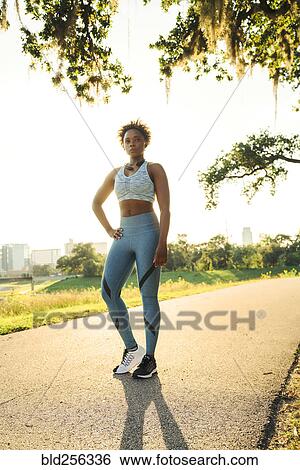 Stock Photograph - Portrait of serious mixed race woman standing on running path in park. Fotosearch