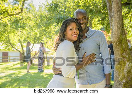 Stock Photo - Portrait of smiling African American couple hugging outdoors. Fotosearch