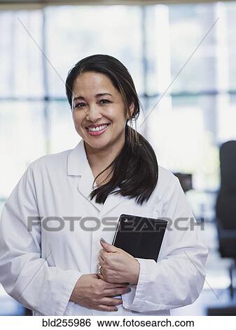 Stock Photograph - Portrait of smiling Asian physical therapist holding digital tablet. Fotosearch