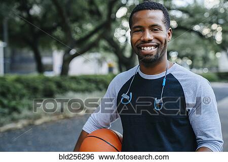 Stock Photograph - Portrait of smiling Black man holding basketball. Fotosearch