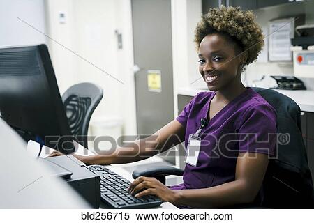 Stock Photography - Portrait of smiling black nurse using computer. Fotosearch