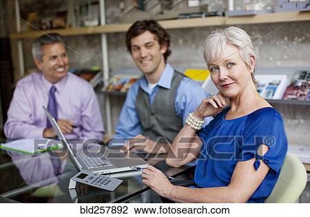 Portrait of smiling businesspeople using laptop in office View Large Photo Image Stock Image - Portrait of smiling businesspeople using laptop in office. Fotosearch