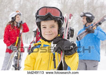 Stock Image - Portrait of smiling Caucasian boy carrying skis. Fotosearch