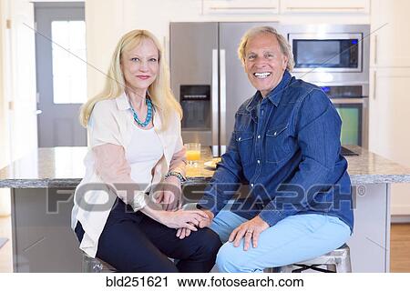 Stock Image - Portrait of smiling Caucasian couple in kitchen. Fotosearch