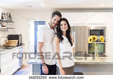 Picture - Portrait of smiling Caucasian couple standing in kitchen. Fotosearch