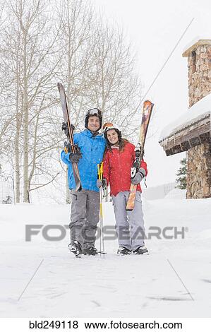 Stock Photo - Portrait of smiling Caucasian couple carrying skis. Fotosearch