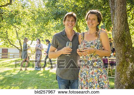 Stock Photo - Portrait of smiling Caucasian couple drinking wine outdoors. Fotosearch
