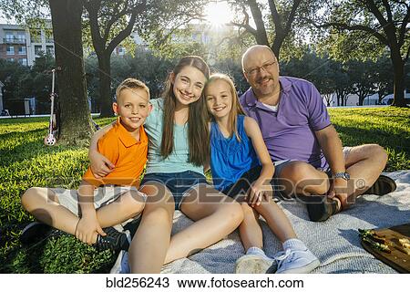 Stock Image - Portrait of smiling Caucasian family in park. Fotosearch