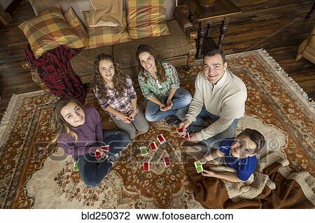 Portrait of smiling Caucasian family sitting on rug playing card game View Large Photo Image Stock Image - Portrait of smiling Caucasian family sitting on rug playing card game. Fotosearch