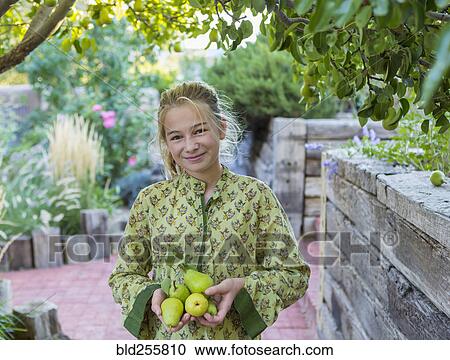 Stock Image - Portrait of smiling Caucasian girl holding pears. Fotosearch