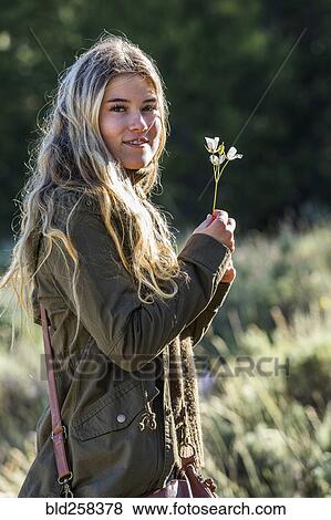 Stock Photo - Portrait of smiling Caucasian girl holding wildflower. Fotosearch