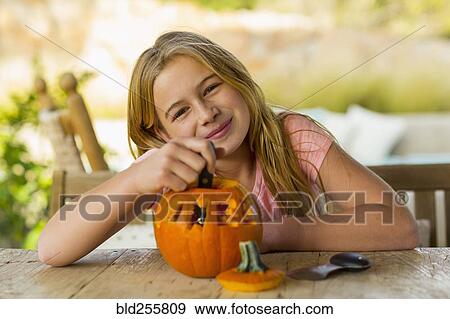 Stock Photo - Portrait of smiling Caucasian girl with carved pumpkin. Fotosearch