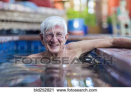 Stock Image - Portrait of smiling Caucasian man in swimming pool. Fotosearch