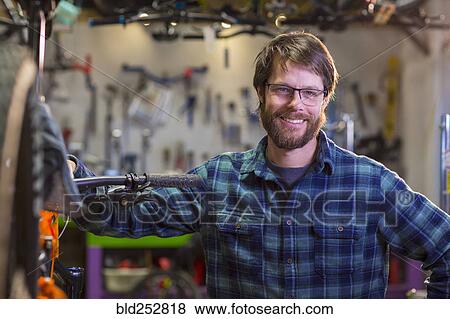 Stock Photo - Portrait of smiling Caucasian man in bicycle shop. Fotosearch